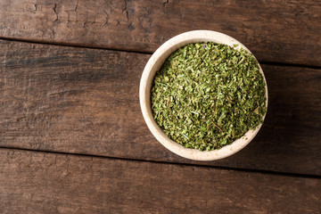 Dried lovage leaves in bowl on wooden table. Close up. Top view