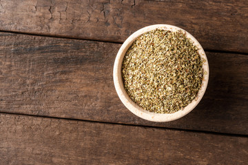 Dried marjoram leaves in bowl on wooden table. Close up. Top view