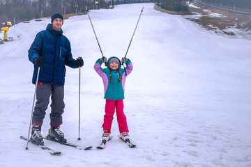 Dad and daughter are skiing. A man and a child have fun in the snow. The family is resting on a snowy winter slope.