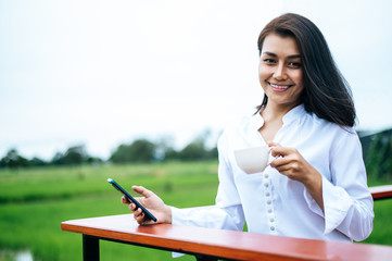 woman standing on a smartphone and holding a coffee cup