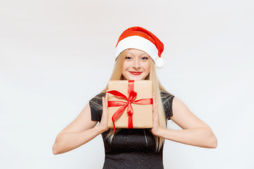 Emotional portrait of a beautiful girl with a gift box in her hands in a Christmas hat on a white background. Space for text. Empty space