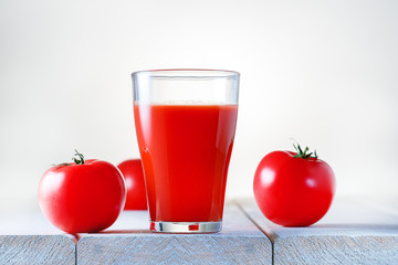 Glass of fresh tomato juice and tomatoes on wooden table, closeup.