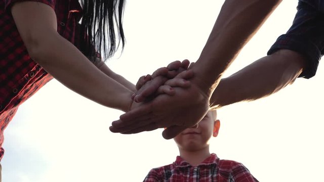 Teamwork. Happy family holding hands against the sky.