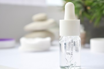 Thyme essential oil. Bottles with extract, fresh green plant leaves. Aromatherapy treatment. Pipette dropping essential oil into a glass bottle on blurred background