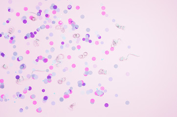 Pink background with purple confetti and silver curls.