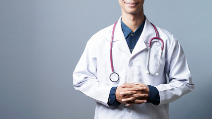 Close up smiling professional doctor with stethoscope in grey background