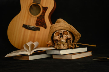 Still life with a heart-shaped book and a skull in the mouth with dry flowers.