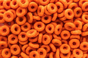 Background of wheat and corn chips with the taste of paprika in the form of rings, top view