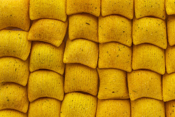 Background of wheat and corn chips with the taste of sour cream and onions in the form of pillows, top view