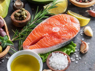 Raw salmon with spices and vegetables on the graphite board.