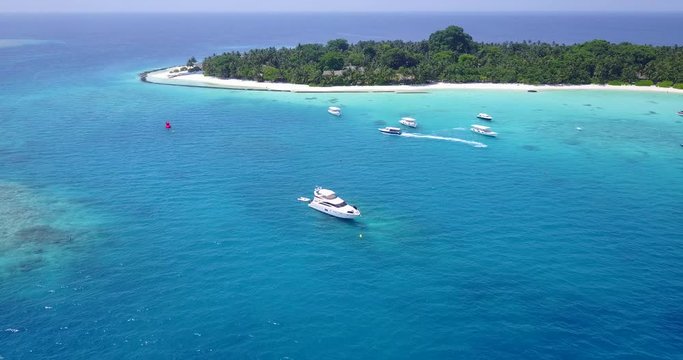 Aerial view video taken by drone of boat cruising in The Maldives lagoon beach with blue turquoise waters
