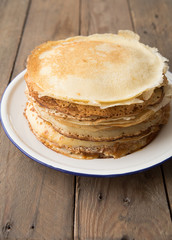 Honey or maple syrup pouring over crepes. Closeup view of stack of thin pancakes, blini