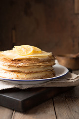Honey or maple syrup pouring over crepes. Closeup view of stack of thin pancakes, blini