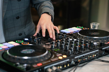DJ hands on stage mixing, disc jockey and mix tracks on sound mixer controller, playing music for party at night club.