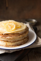 Honey or maple syrup pouring over crepes. Closeup view of stack of thin pancakes, blini