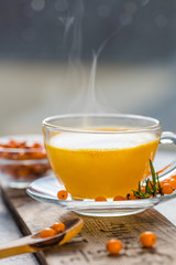Sea buckthorn tea  in a glass cup before window.   Herbal vitamin beverage