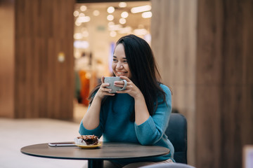Cute plus size woman resting in cafe inside city mall