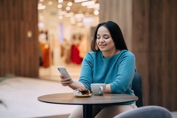 Cute plus size woman talking by mobile phone while resting in cafe inside city mall
