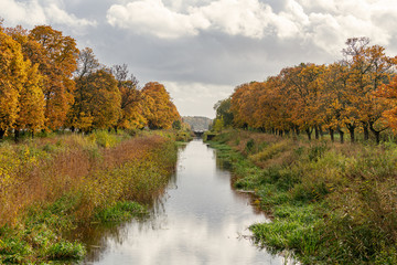 Canal in Sweden with autumn colored oak trees along the river bank