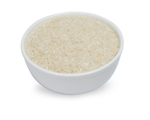 uncooked rice in white ceramic bowl on white background.