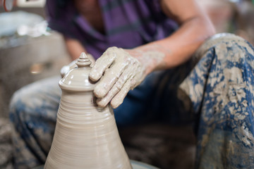  Earthenware hands of potter creating a jar in thailand