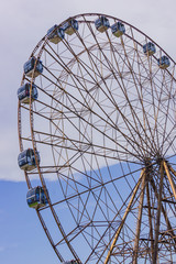 Big atraktsion ferris wheel on the background of a beautiful blue sky with clouds