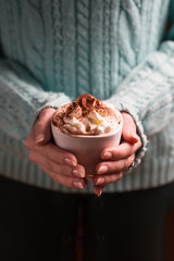 Woman holding mug of cocoa drink with whipped cream in hands