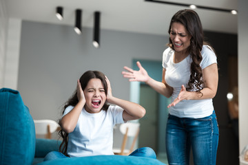 young beautiful woman having an argument with her teen daughter shouting loud in the living room