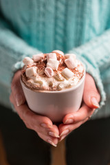 Woman holding mug of cocoa drink with whipped cream in hands