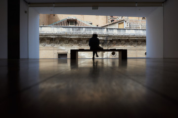   Young woman sitting in front of a large window in a dark room.