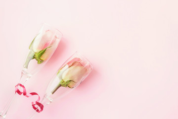 Roses in wineglasses on a pink background. Background for holiday, birthday, wedding, Valentine's day, Women's Day. Top view, flat lay composition. Copy space for text or design.