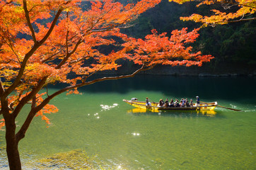Fototapeta premium Boatman punting the boat at river. Arashiyama in autumn season along the river in Kyoto, Japan.
