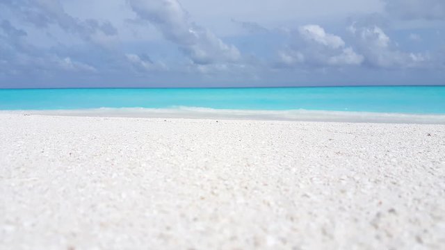 loopable white sand tropical beach background, crystal clear aquamarine sea water, sky with clouds. copy space