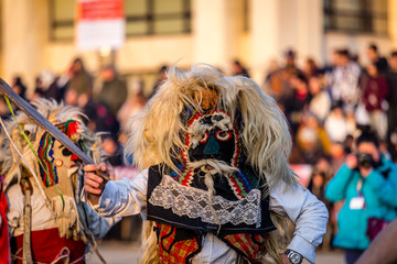 Fototapeta na wymiar Mummers perform rituals to scare evil spirits at Surva festival at Pernik in Bulgaria. The people with the masks are called Kuker (kukeri). Mask from wool .