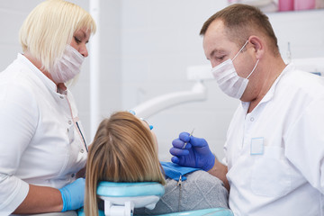 Obraz premium Doctor dentist treats teeth of a beautiful young girl patient. The girl on reception at the dentist. Doctor dentist treats tooth