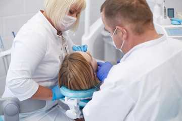 Fototapeta na wymiar Doctor dentist treats teeth of a beautiful young girl patient. The girl on reception at the dentist. Doctor dentist treats tooth