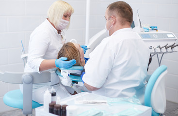 Obraz premium Doctor dentist treats teeth of a beautiful young girl patient. The girl on reception at the dentist. Doctor dentist treats tooth