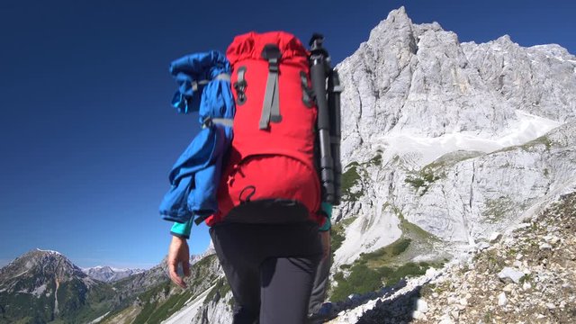 4K outdoor footage, two landscape photographers with backpacks on hiking tour high up in beautiful alpine mountains on sunny day in autumn with clear blue sky