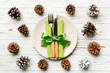 New Year set of plate and utensil on wooden background. Top view of holiday dinner decorated with pine cones. Christmas time concept