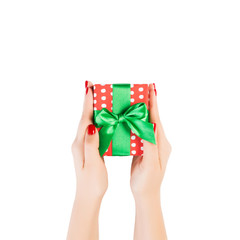 Woman hands give wrapped Christmas or other holiday handmade present in red paper with Green ribbon. Isolated on white background, top view. thanksgiving Gift box concept