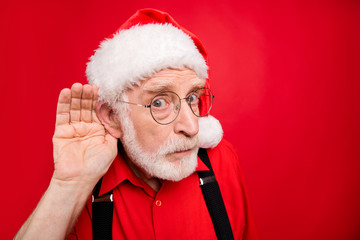 Close-up portrait of his he nice serious suspicious bearded Santa Claus trying to overhear what you say speak tell isolated over bright vivid shine vibrant red background