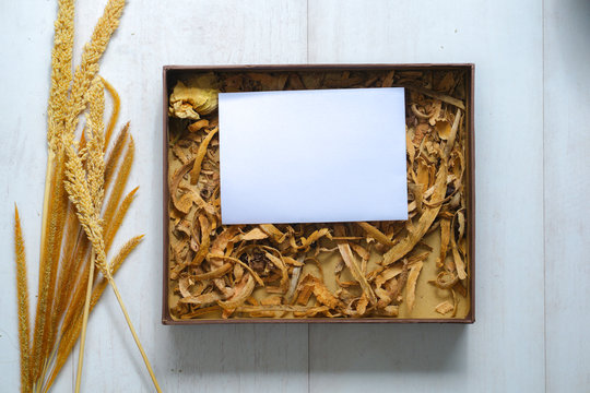 Flat lay composition for autumn holidays greeting cards. Pine cones, wheak, leaves, flowers in a wooden box on the wooden background. Top view, copy space.