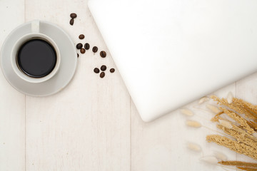 Home office desk with laptop, cup of coffe, bouquet of wheat spikelets on a wooden background