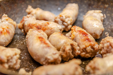Sausages fried in a frying pan close up