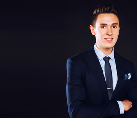 young pretty business man standing on black background, modern hairstyle, talking on phone emotional