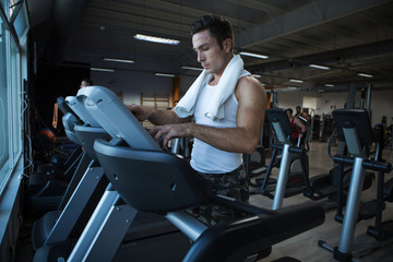 Fototapeta na wymiar Muscular man using exercise machine in gym