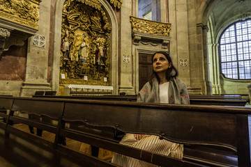 A believing woman sits on a bench in the church and prays to God. Girl praying in a church of...