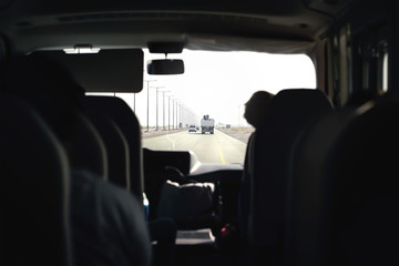Bus on highway. Coach, shuttle or minivan. Airport transfer with taxi van. Passenger interior view from back seat. Tourist tour excursion. Public transport. Inside car. Motorway traffic.