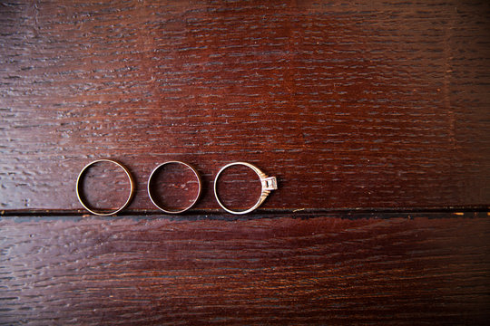 three gold wedding rings on a wooden bench