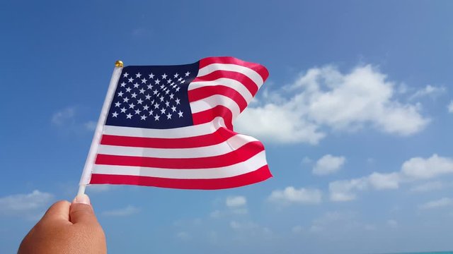 Hand holding an American flag against the wind on a sunny day  4K